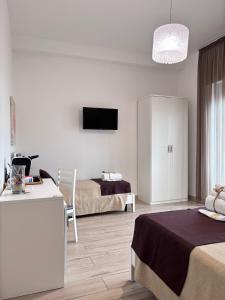 a hotel room with two beds and a flat screen tv at Faro Bianco Gallipoli - Suites & Apartments in Gallipoli