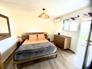 a bedroom with a bed and a dresser and a window at Sunset View - Panoramic Sea View - Deshaies in Deshaies