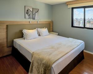 a large bed in a room with a window at Rio Hotel by Bourbon Batel - Curitiba in Curitiba