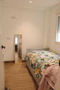 a bedroom with a bed with a floral bedspread and a mirror at Pretodomar3 in A Coruña