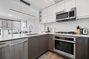 a kitchen with stainless steel appliances and white cabinets at Stylish Serenity 1BR Kensington Condo wParking in Calgary