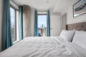 a bedroom with a large bed with a large window at Exquisite 2 Bed Condo near DT Core WFree Parking in Calgary