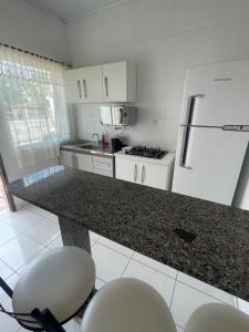 a white kitchen with a counter and a refrigerator at Pousada 4 Estações in Canoinhas