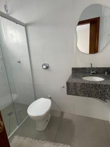 a bathroom with a toilet and a sink and a mirror at Pousada 4 Estações in Canoinhas