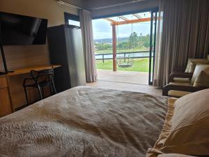 a bedroom with a bed and a view of a balcony at Riviera Barão de Antonina - Chalés na Represa - Piscina vista incrível in Barão de Antonina