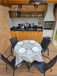 a dining table with four chairs and a kitchen at Riviera Barão de Antonina - Chalés na Represa - Piscina vista incrível in Barão de Antonina +24 photos
