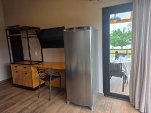 a kitchen with a stainless steel refrigerator next to a table at Riviera Barão de Antonina - Chalés na Represa - Piscina vista incrível in Barão de Antonina