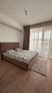 a bedroom with a bed in a room with windows at Warm apartament 3 in Bucharest