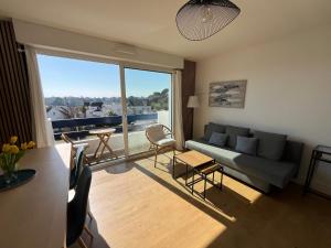 a living room with a couch and a large window at Appartement vue mer in Bénodet