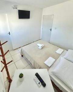 a room with two beds and a remote control on a table at Quarto 02 - Pousada Canaã in Recife