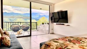a bedroom with a view of a balcony with a television at Hotel El Mirador del Cocora in Salento