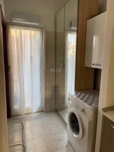 eine Waschküche mit Waschmaschine und Dusche in der Unterkunft Piccolo Relax in Meina