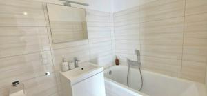 ein weißes Badezimmer mit Badewanne, Waschbecken und Badewanne in der Unterkunft Zakątek w Centrum Suwałk in Suwałki
