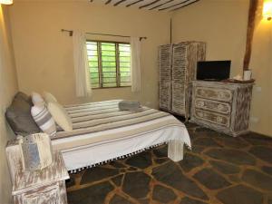 a bedroom with a large bed with a dresser and a window at 1, 2 bed bungalow Watamu in Watamu