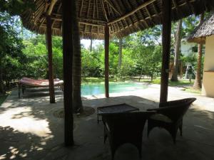 a patio with a table and chairs and a pool at 1, 2 bed bungalow Watamu in Watamu