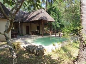 a house with a swimming pool and a hut at 1, 2 bed bungalow Watamu in Watamu