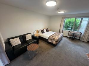 a bedroom with a bed and a couch and a table at ASURE Centrepoint Motel in Christchurch