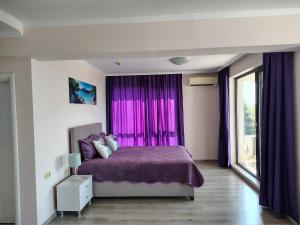 a bedroom with a purple bed and purple curtains at Апартамент Ивела in Balchik +18 photos