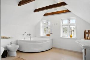 a white bathroom with a large tub and two windows at LF11975-Struer-Havstokken-12 in Vemb +23 photos