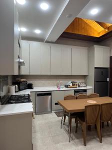a kitchen with white cabinets and a wooden table at Bait Ajloun in Khirbat Shīn