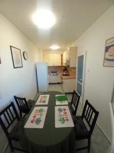 a dining room with a table and chairs and a kitchen at Fasor Apartman in Kaposvár +11 photos