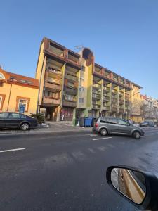 a building with cars parked on the side of a street at Fasor Apartman in Kaposvár