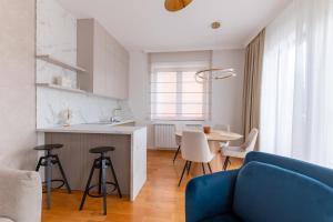 a living room with a blue couch and a kitchen at Apartman Maxim in Palić