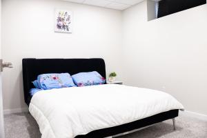 a white bedroom with a bed with blue pillows at Bright Modern Suite in Bonavista, Private Entrance with Free Parking in Winnipeg