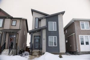 a house with a black door in the snow at Bright Modern Suite in Bonavista, Private Entrance with Free Parking in Winnipeg