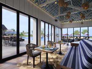 a dining room with tables and chairs and windows at Pullman Lombok Merujani Mandalika Beach Resort in Kuta Lombok