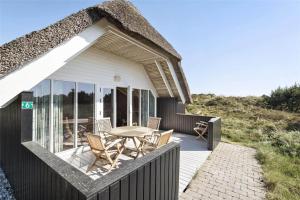 a house with a deck with a table and chairs at BV102-Blavand-Nordslugen-6 in Blåvand