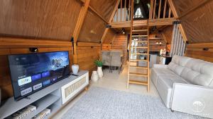 a living room with a couch and a television at Refúgio em Gramado | cabana c/ hidromassagem in Gramado