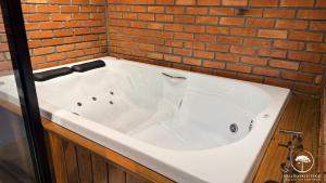 a white bath tub in a room with a brick wall at Refúgio em Gramado | cabana c/ hidromassagem in Gramado +44 photos