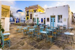 a group of tables and chairs in front of a building at Villa fisfiri 1 in Serifos Chora