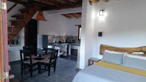 a bedroom with a bed and a table and a kitchen at Cabañas Paqa Paqa in Maimará