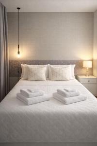 a white bed with three towels on top of it at Aconchego in Maringá