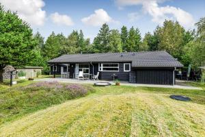 a black cabin with a patio and a yard at BV406-Blavand-Tvaervaenget-2 in Blåvand