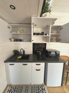 a kitchen with white cabinets and a black counter top at Domek w górach Tiny House Forest Jacuzzi/widoki in Lipnica Wielka