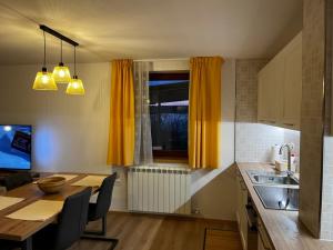 a kitchen with a dining table and yellow curtains at Rumena hiša in Trnovo