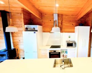 a kitchen with white appliances and wooden walls at Absolute Tranquility - surrounded by native bush in Kaiuma +11 photos