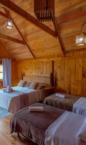 a room with three beds in a wooden building at Pousada Rural Pavão - Suites e Chalés in Urubici