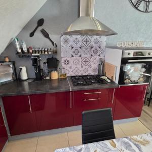 a kitchen with red cabinets and a stove at Gîte Vallée de Munster 3 étoiles chez Flavie & Ludo in Muhlbach-sur-Munster +16 photos