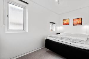a white bedroom with a bed and a window at BV230-Blavand-Vesterhavsparken-35 in Blåvand