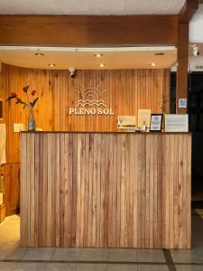 a wooden bar in a restaurant with a sign on it at Hotel Pleno Sol in Villa Gesell