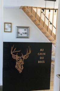 a sign with a deer head on a wall next to a staircase at Au Coin du Bois in Manhay