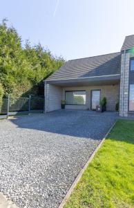 a house with a gravel driveway in front of it at Au Coin du Bois in Manhay