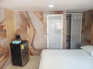 a bedroom with a white bed and a painting on the wall at Hostal Doña Betty 2 in Cartagena de Indias