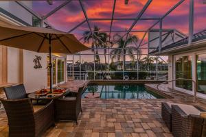 a house with a pool and a table with an umbrella at Villa Hibiscus-Waterfront-Free Heated Pool-Dock-Bikes-Other Amenities in Punta Gorda