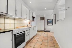a kitchen with white cabinets and a tile floor at BV255-Blavand-Vesterhavsparken-39 in Blåvand +13 photos