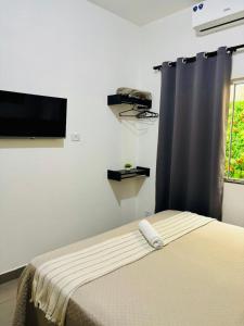 a bedroom with a bed and a flat screen tv at VOER - BR Flat Hospedaria in Sete Lagoas